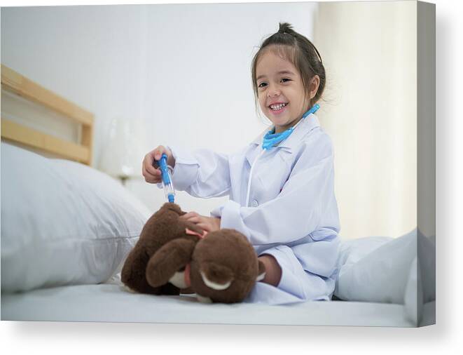 Doctor Canvas Print featuring the photograph Small girl inject the Teddy Bear by doctor toy set on the bed in by Anek Suwannaphoom