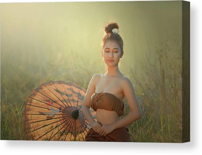 Light Background Canvas Print featuring the photograph Woman meditating in lotus position with golden light. by Somchai Sanvongchaiya