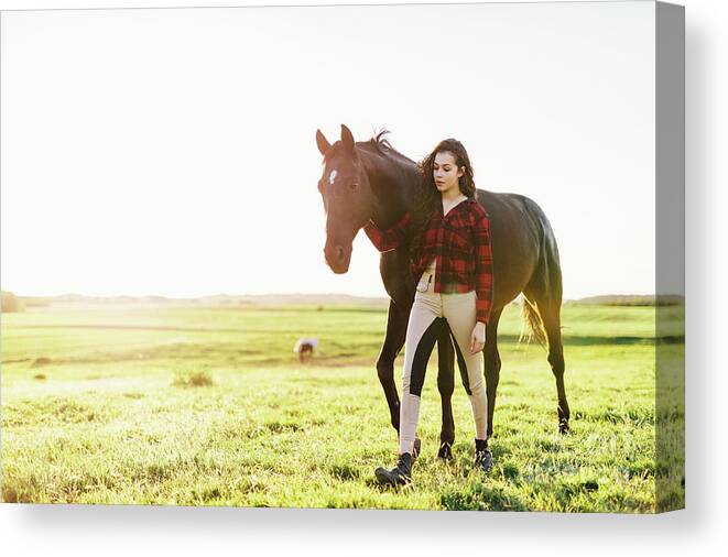 Woman Canvas Print featuring the photograph Young woman standing next to her black horse by Michal Bednarek