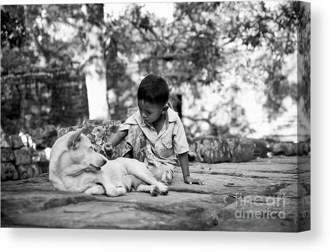 2015 Canvas Print featuring the photograph Cambodian boy near some ruins playing with his dog. #1 by Joaquin Corbalan