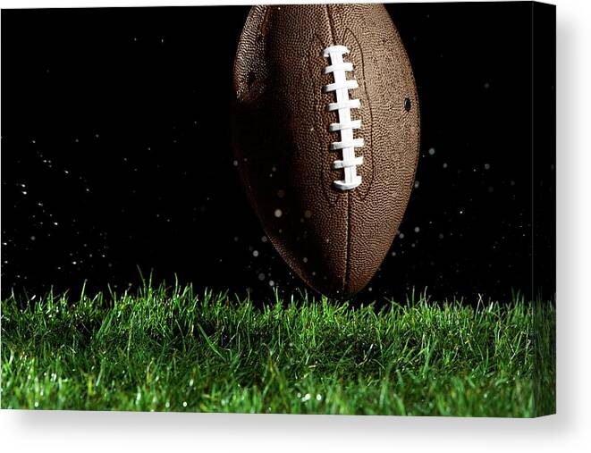Grass Canvas Print featuring the photograph Football In Motion Over Grass by Thomas Northcut