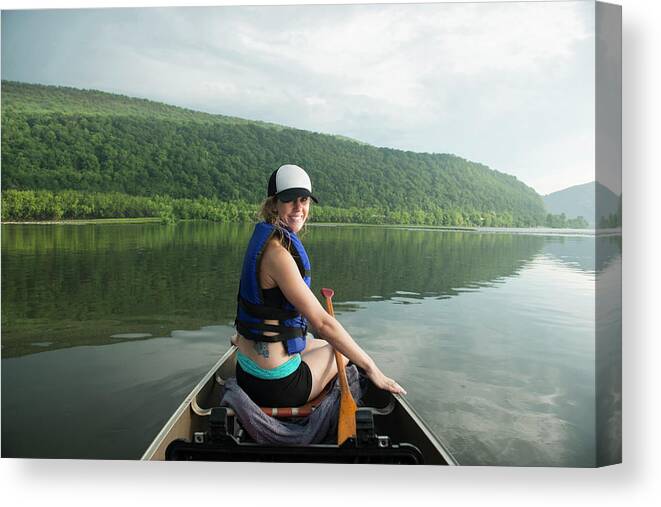 Woman Canvas Print featuring the photograph Portrait Of Smiling Woman Canoeing On River Against Cloudy Sky by Cavan Images