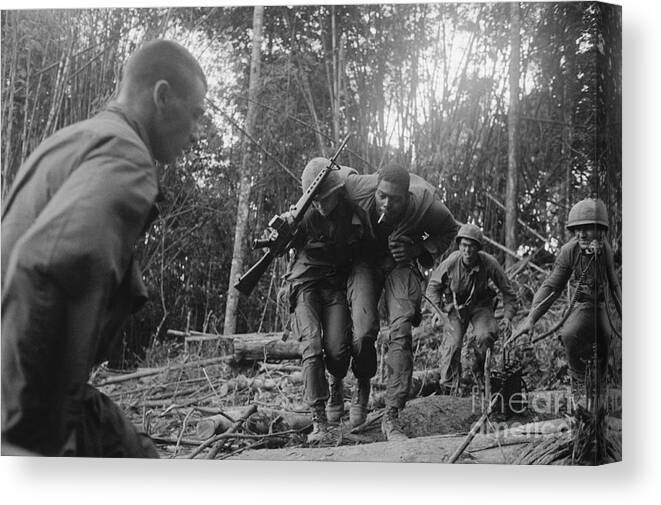 Vietnam War Canvas Print featuring the photograph Wounded Soldier Being Carried To Safety by Bettmann