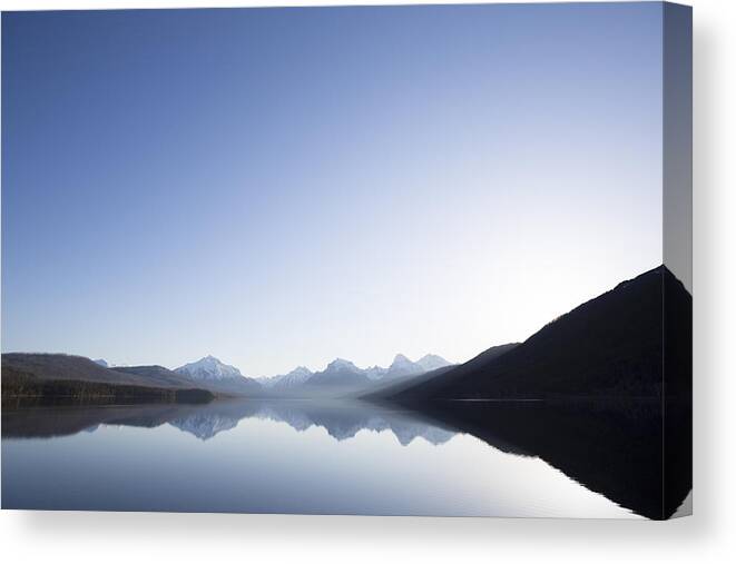 Snow Canvas Print featuring the photograph A calm morning before sunrise on Lake McDonald in Glacier National Park. #1 by Craig Moore