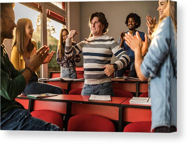 University Canvas Print featuring the photograph Young students applauding their friend in the classroom. #1 by Skynesher