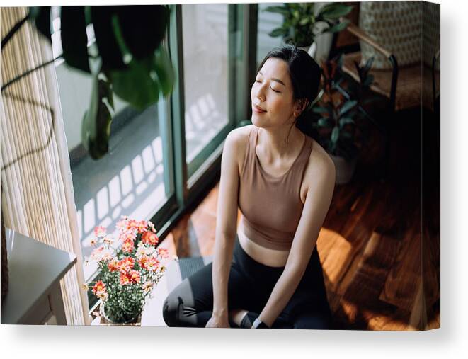 Tranquility Canvas Print featuring the photograph Active young Asian sports woman taking a break after working out at home, sitting on exercise mat taking a deep breath with her eyes closed. Sports and exercise routine. Health, fitness and wellness concept by D3sign