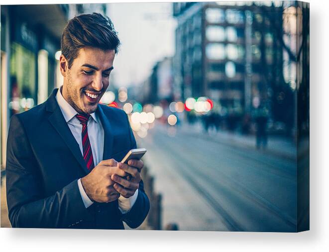 Employment And Labor Canvas Print featuring the photograph Businessman texting outdoors in the evening by Pixelfit