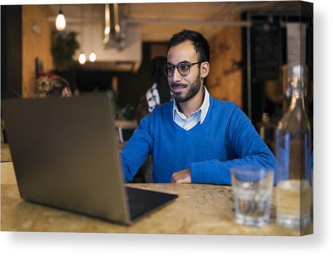 Working Canvas Print featuring the photograph Businessman using laptop in cafe by Compassionate Eye Foundation