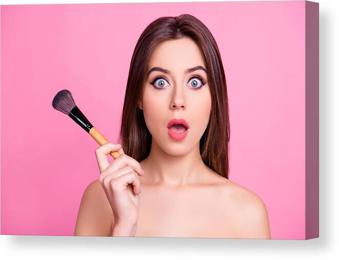Spa Canvas Print featuring the photograph Close up portrait of shocked beautiful attractive pop-eyed pretty surprised scared make up artist holding a brush for blusher and powder in a hand, isolated on pink background by Deagreez