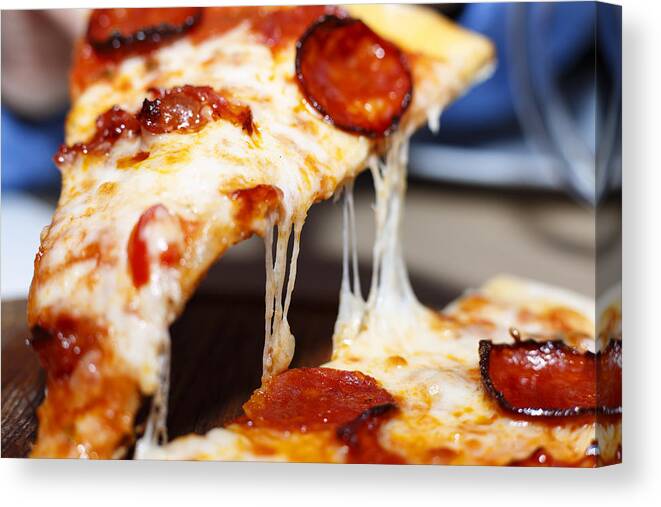 Pepperoni Pizza Canvas Print featuring the photograph Closeup of a piece of pepperoni pizza. Italian pizza. by Gannamartysheva
