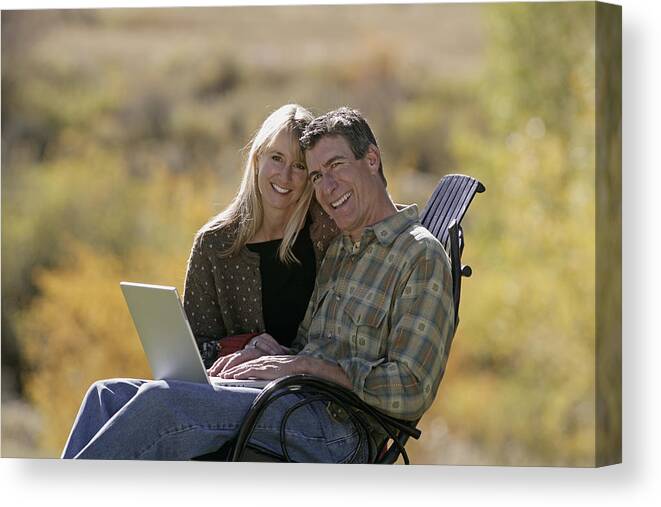 Three Quarter Length Canvas Print featuring the photograph Couple using laptop by Comstock Images