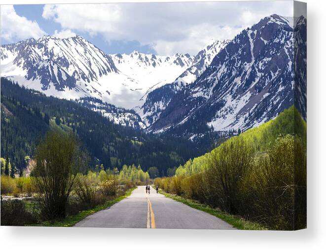 Aspen Canvas Print featuring the photograph Distant people bicycling on road to mountain by Julien McRoberts