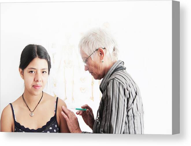 Holding Canvas Print featuring the photograph Doctor giving teenage girl shot by Sigrid Gombert