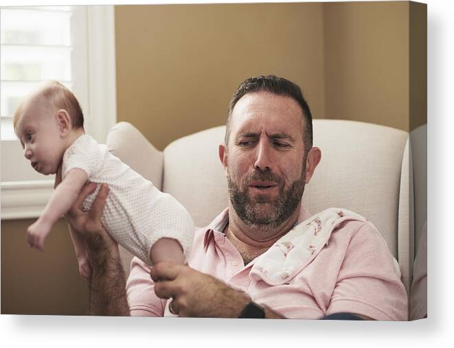 Mature Adult Canvas Print featuring the photograph Father holding baby with dirty diaper by The Good Brigade