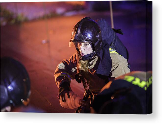 Working Canvas Print featuring the photograph Female firefighter helping injured by Vm