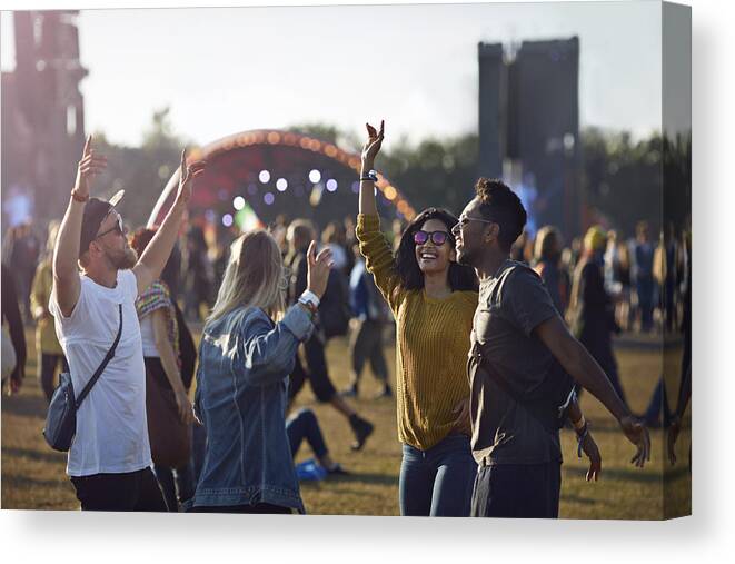 Young Men Canvas Print featuring the photograph Friends dancing at festival with arms in air by Klaus Vedfelt
