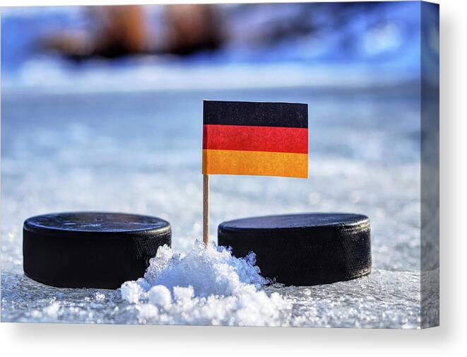 Germany Canvas Print featuring the photograph Germany flag on toothpick between two hockey pucks. Winter classic. Flag on frozen pond on unkempt ice. Traditional pucks for international matches. by Vaclav Sonnek
