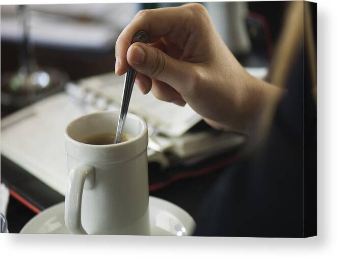 Mid Adult Women Canvas Print featuring the photograph Hand stirring coffee, agenda on table in background, close-up by PhotoAlto