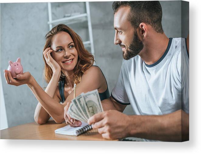 Strategy Canvas Print featuring the photograph Happy Couple Planning Family Budget And Looking At Each Other In Living Room by LightFieldStudios