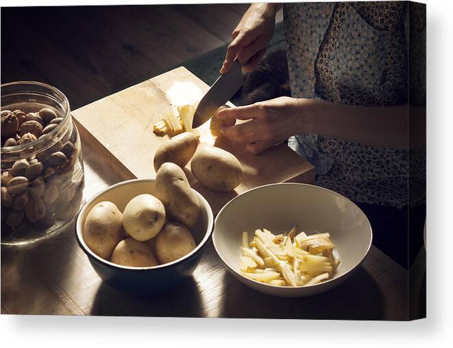 Shadow Canvas Print featuring the photograph High angle view of woman cutting potatoes on cutting board at home by Cavan Images