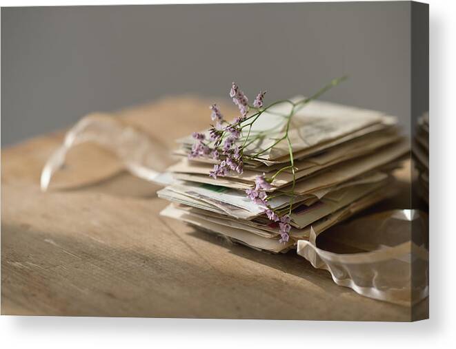 Large Group Of Objects Canvas Print featuring the photograph Lavender stem on stack of letters by Tetra Images