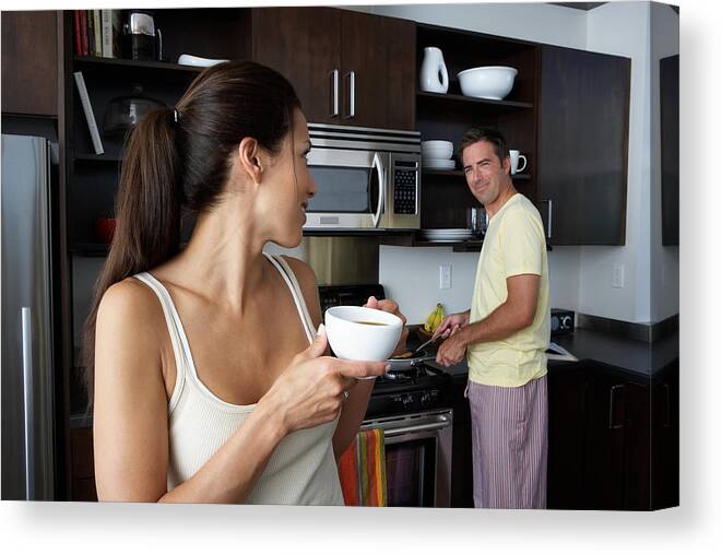 Breakfast Canvas Print featuring the photograph Man and woman preparing breakfast and smiling at one another by Thomas Northcut