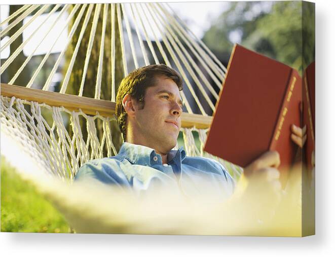 Tranquility Canvas Print featuring the photograph Man laying in hammock reading book by Paul Bradbury