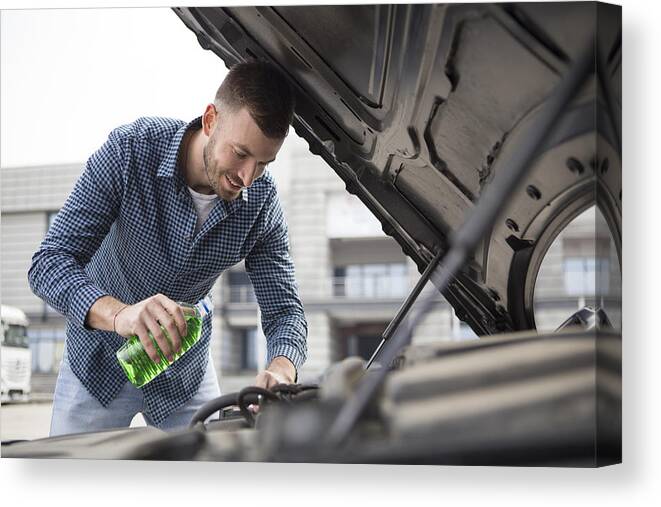 Working Canvas Print featuring the photograph Man pouring coolant by GoodLifeStudio