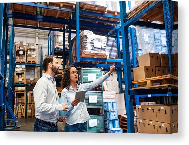 Working Canvas Print featuring the photograph Manager and supervisor taking inventory in warehouse by Alvarez