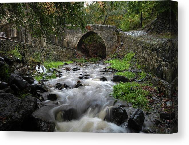 River Canvas Print featuring the photograph Medieval stoned bridge water flowing in the river. by Michalakis Ppalis