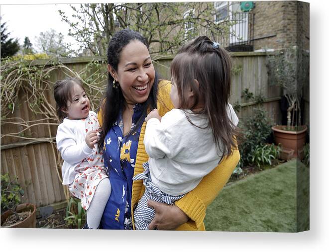 Toddler Canvas Print featuring the photograph Mother holding twin daughters with Downs Syndrome by Nick David