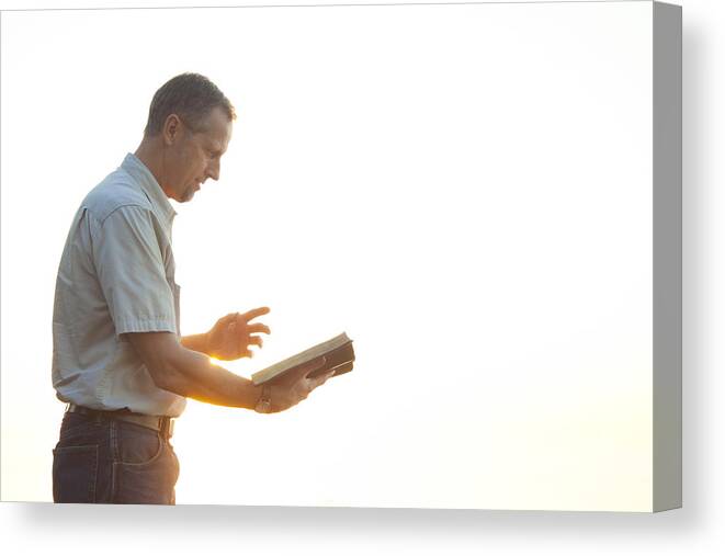 Education Canvas Print featuring the photograph Pastor casually dressed walking in sunlight reading Bible by Juanestey