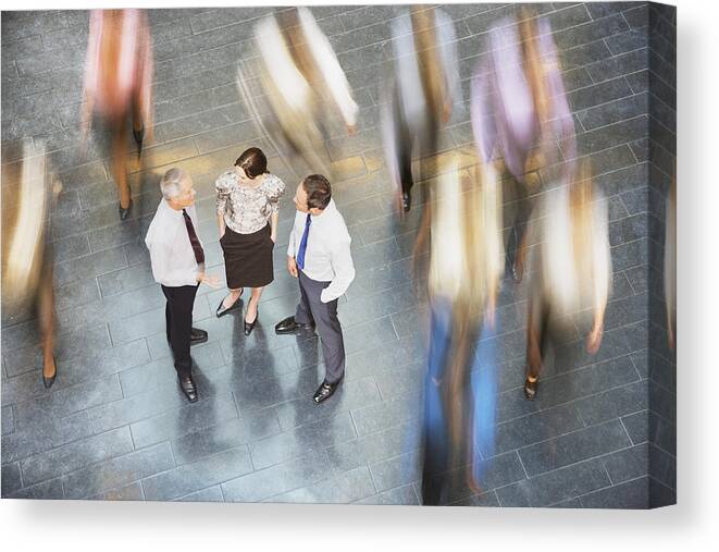 Working Canvas Print featuring the photograph People rushing past business people talking by Daly and Newton