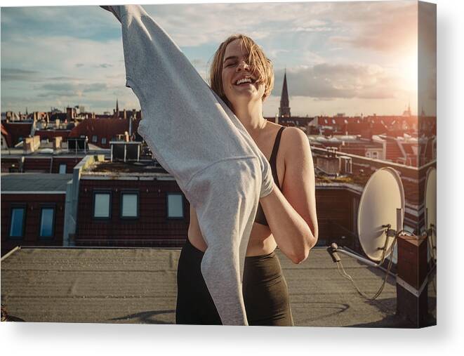 Cool Attitude Canvas Print featuring the photograph Portrait of smiling woman wearing t-shirt on rooftop against dramatic sky by Maskot