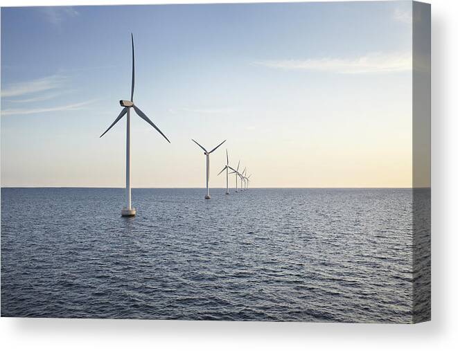 Environmental Conservation Canvas Print featuring the photograph Row of winturbines in the sea shot in the sunset by Klaus Vedfelt