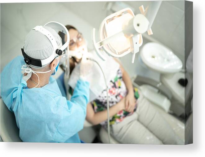 Expertise Canvas Print featuring the photograph Senior dentist examining the teeth of a young woman by FG Trade