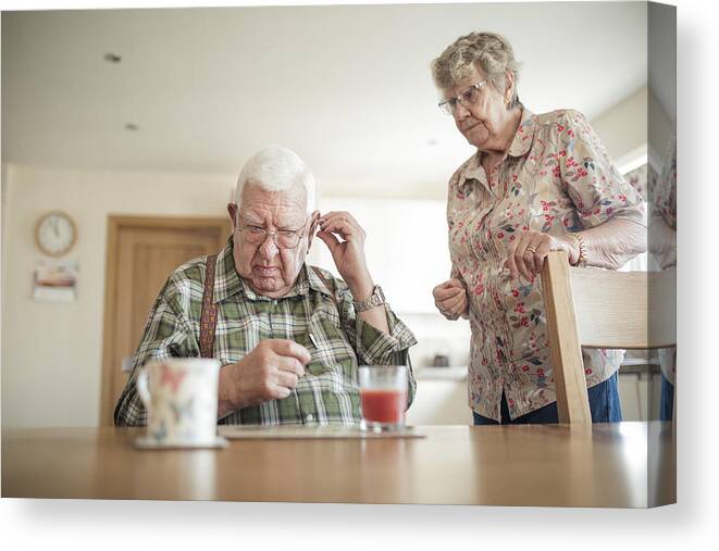 Breakfast Canvas Print featuring the photograph Senior Man Inserting His Hearing Aid by SolStock