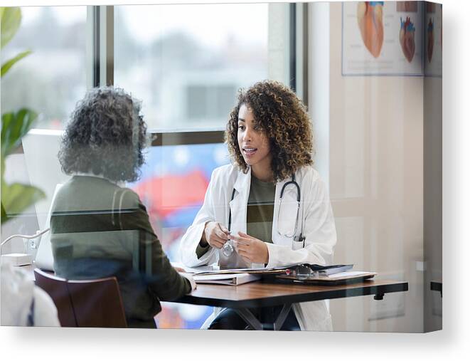 Internet Canvas Print featuring the photograph Sitting in office, doctor has serious conversation with patient by SDI Productions