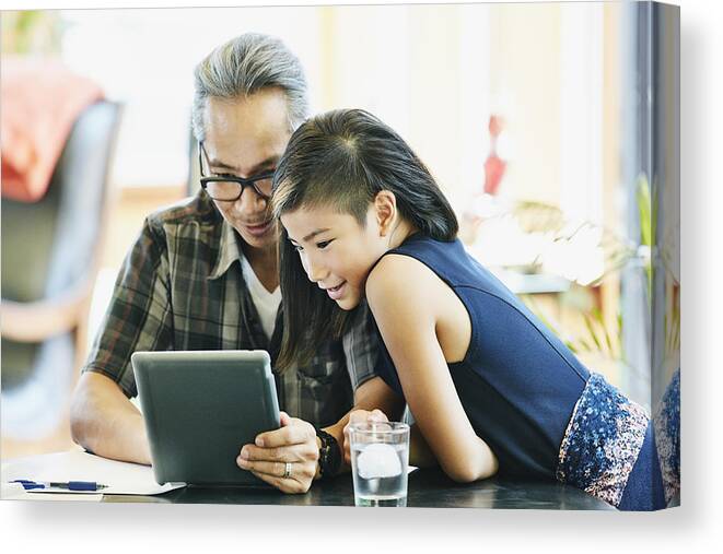 Plaid Shirt Canvas Print featuring the photograph Smiling girl and father making video call on digital tablet while sitting in dining room by Thomas Barwick