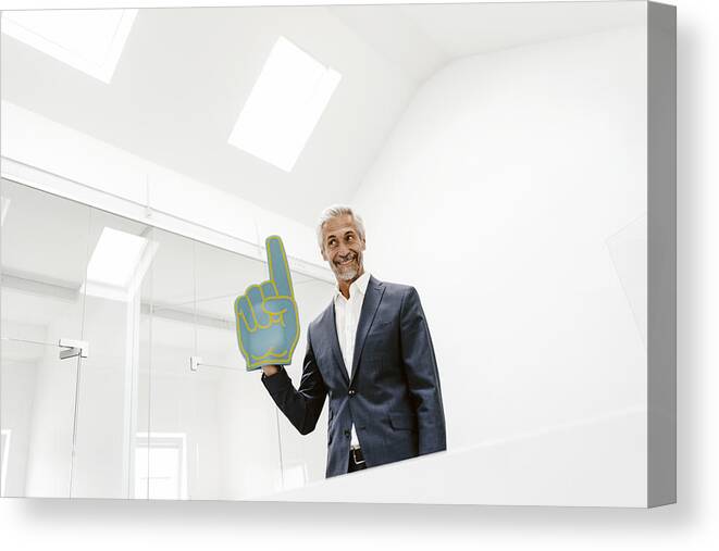 Expertise Canvas Print featuring the photograph Smiling mature businessman holding toy hand in office by Westend61