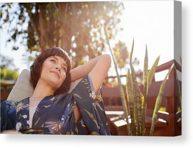 People Canvas Print featuring the photograph Smiling young woman lying back in a patio deck chair by Goodboy Picture Company