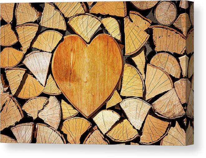 Pile Canvas Print featuring the photograph Stack of firewood with a wooden heart by Bernhard Schaffer