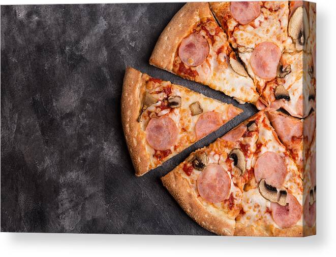 Heat Canvas Print featuring the photograph Tasty sliced pizza on black concrete background. Top view of hot pizza. With copy space for text, flat lay. Fast homemade food, home delivery. by Yulia Naumenko