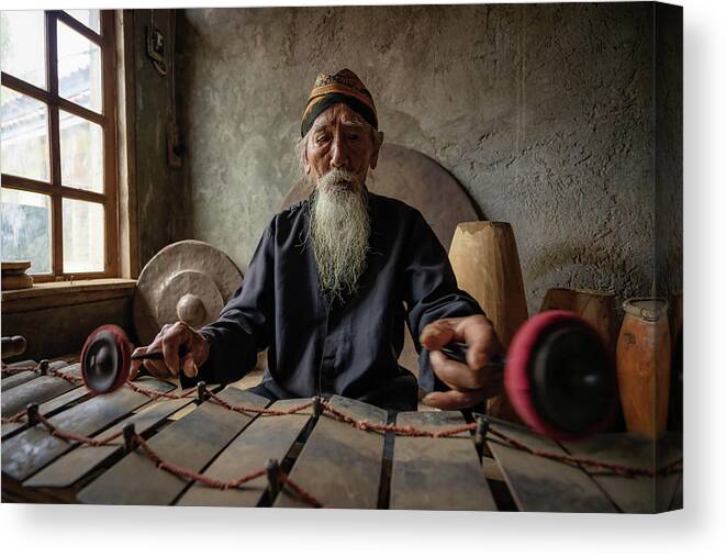 Gamelan Canvas Print featuring the photograph The gamelan maestro Ki Suripto giving a performance in his simple house in Salatiga, Indonesia by Anges Van der Logt