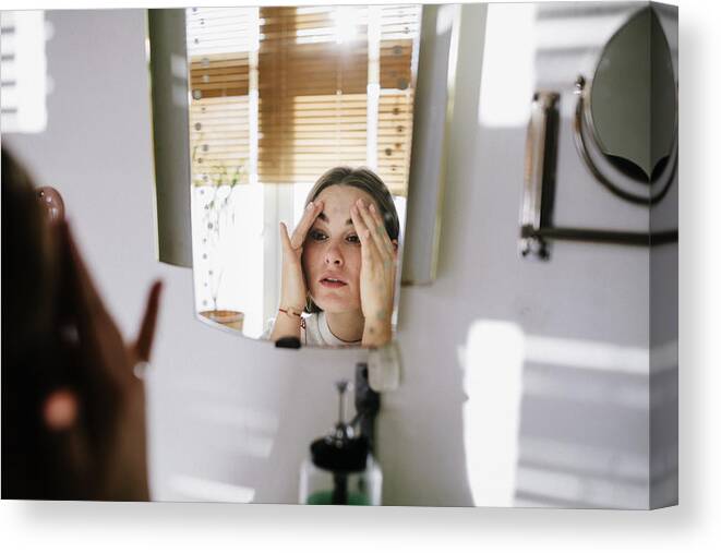 Vanity Mirror Canvas Print featuring the photograph Woman looking in bathroom mirror by Willie B. Thomas