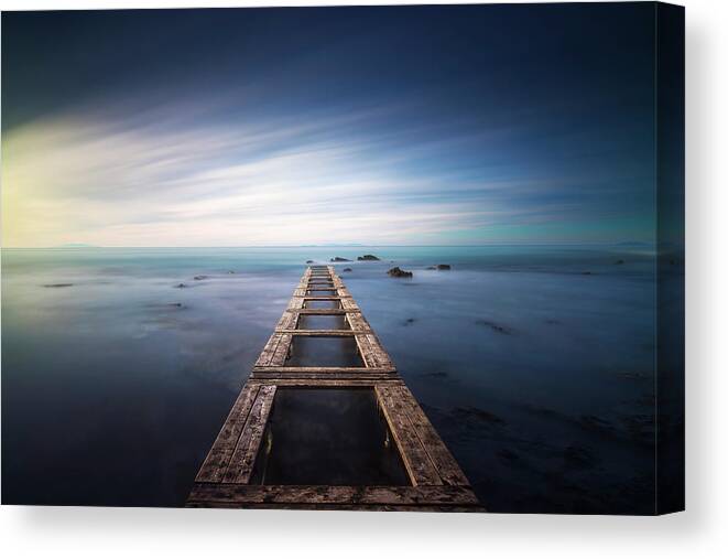 Sea Canvas Print featuring the photograph Wooden pier remains in a blue sea. Long Exposure. by Stefano Orazzini