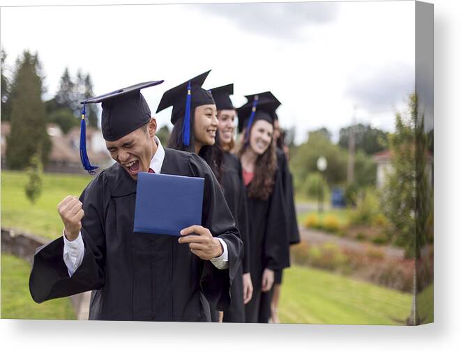Graduation Gown Canvas Print featuring the photograph Young ethnic male celebrates after receiving his diploma by FatCamera