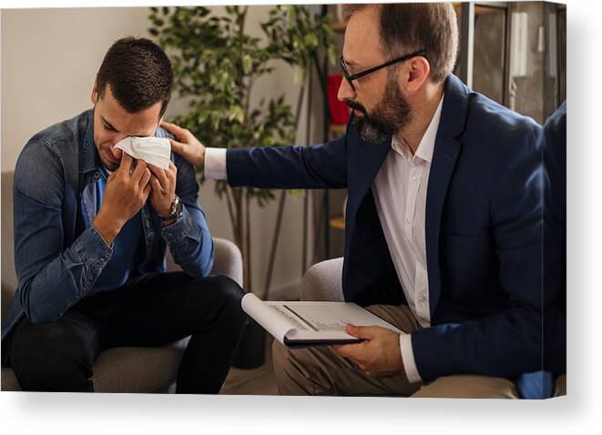 Young Men Canvas Print featuring the photograph Young man crying during psychotherapy by Mixetto