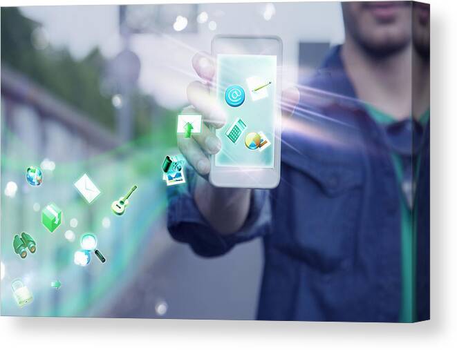 People Canvas Print featuring the photograph Young man holding up smartphone with apps and icons coming out of it by Innocenti
