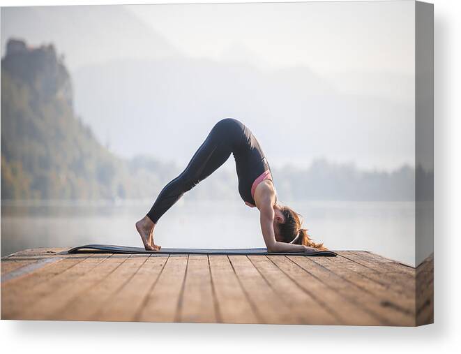 Tranquility Canvas Print featuring the photograph Young Woman in Dolphin Pose on Pier Overlooking Lake Bled by AzmanL